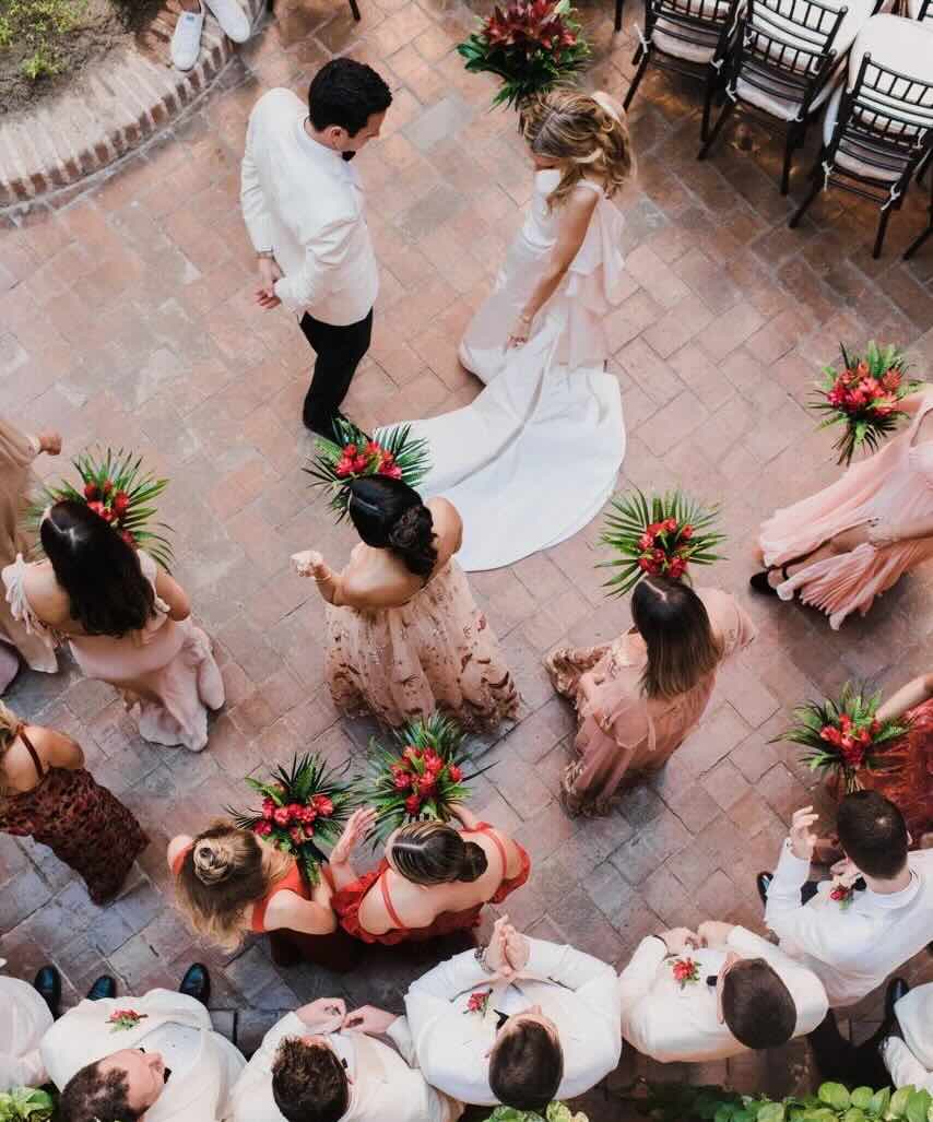 Overhead image of a wedding party standing on a brick floor.