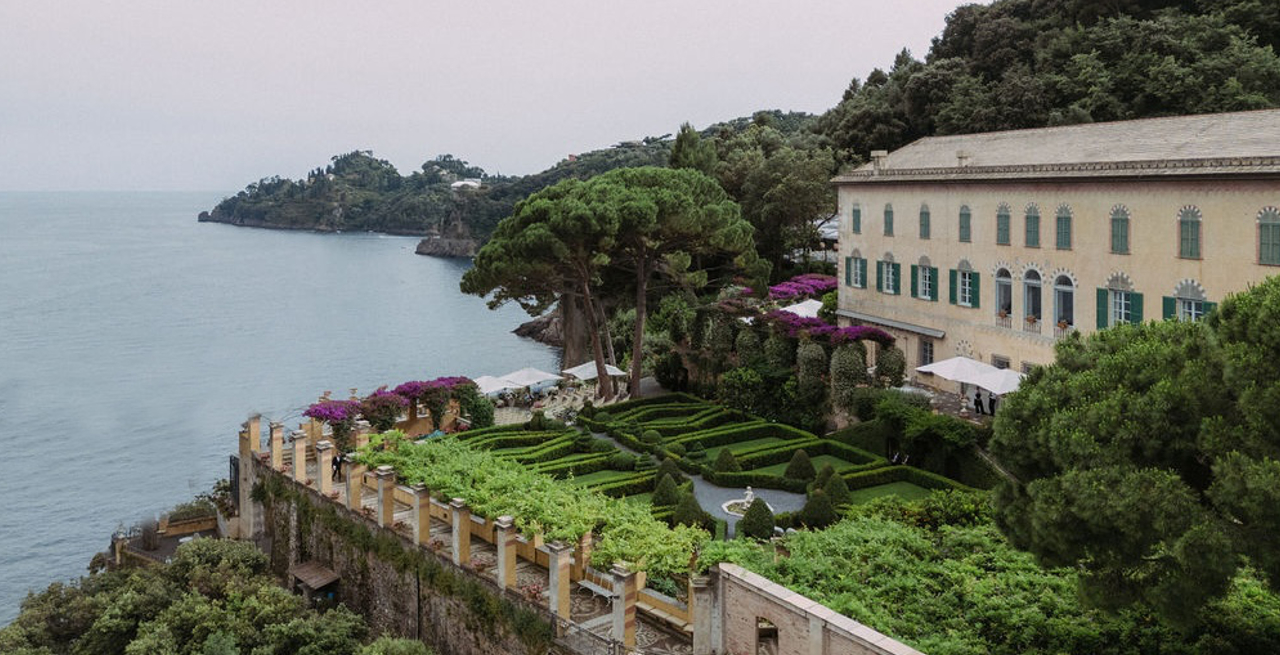Ornate multi-level building with a garden near the coastline.